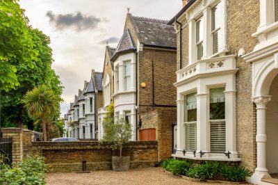 Elegant London townhouses with brick facades, bay windows, and private front gardens