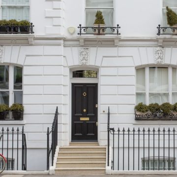 Elegant white London townhouse with black front door, iron railings, and potted plants, representing trusted house sitting London